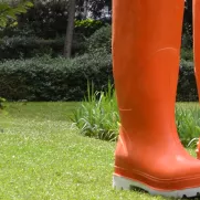 Photographie d'une sculpture représentant une paire de bottes de jardin oranges surdimensionnées sur une pelouse