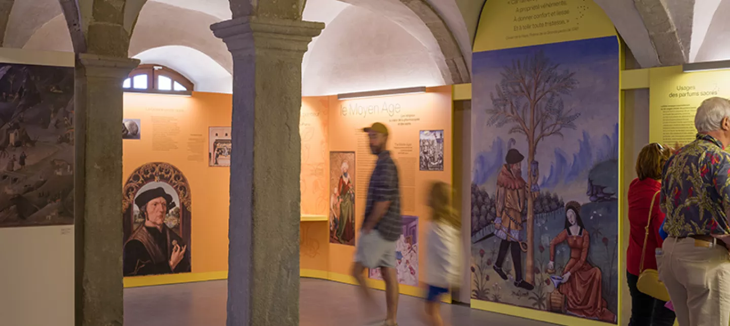 Photographie d'une salle d'exposition à Saint-Antoine l'Abbaye avec quelques visiteurs