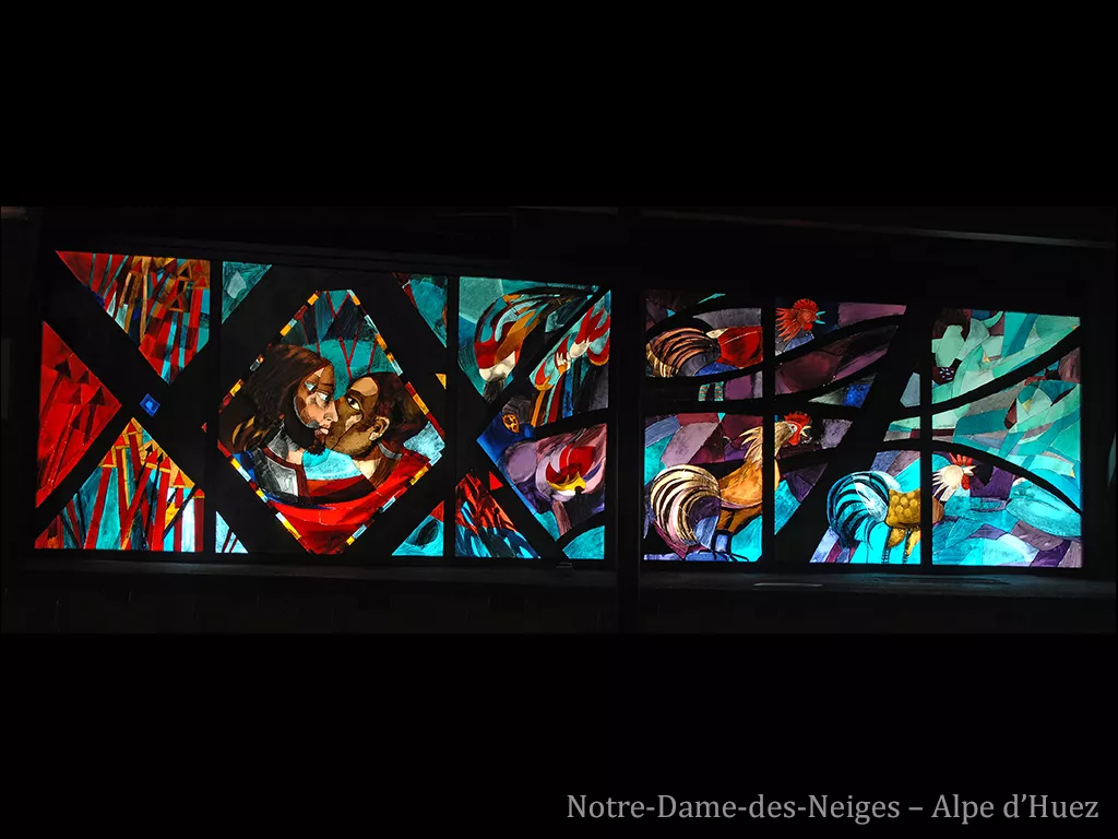 A gauche, Judas embrasse Jésus. A droite, des coqs sont représentés. Vitrail sur fond rouge, bleu et violet.