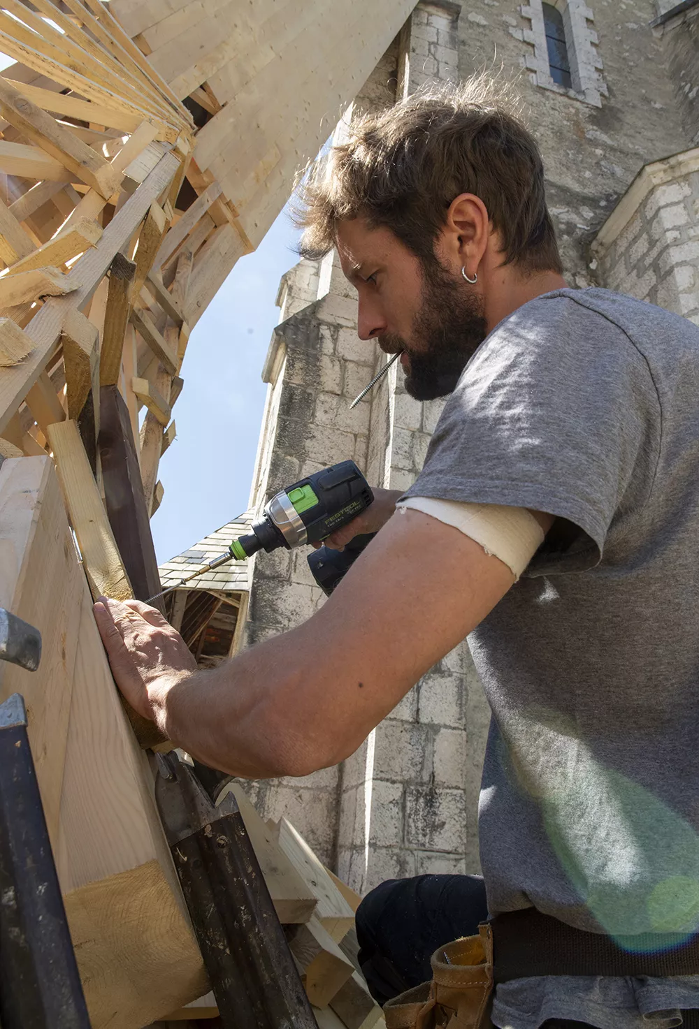 Simon Augade travail sur son oeuvre devant le musée. L'artiste vise les chutes de bois sur la structure de son oeuvre