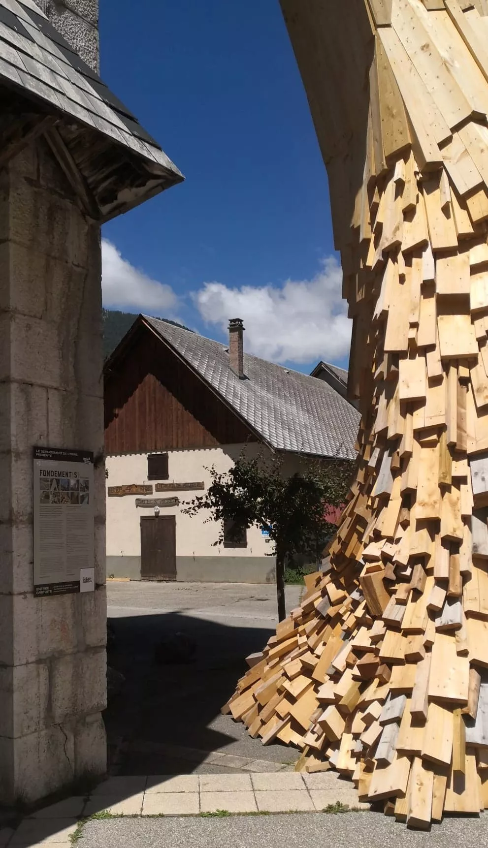 A gauche, le cartel de l'oeuvre sur le mur de l'église et à droite, une partie de l'oeuvre de Simon Augade