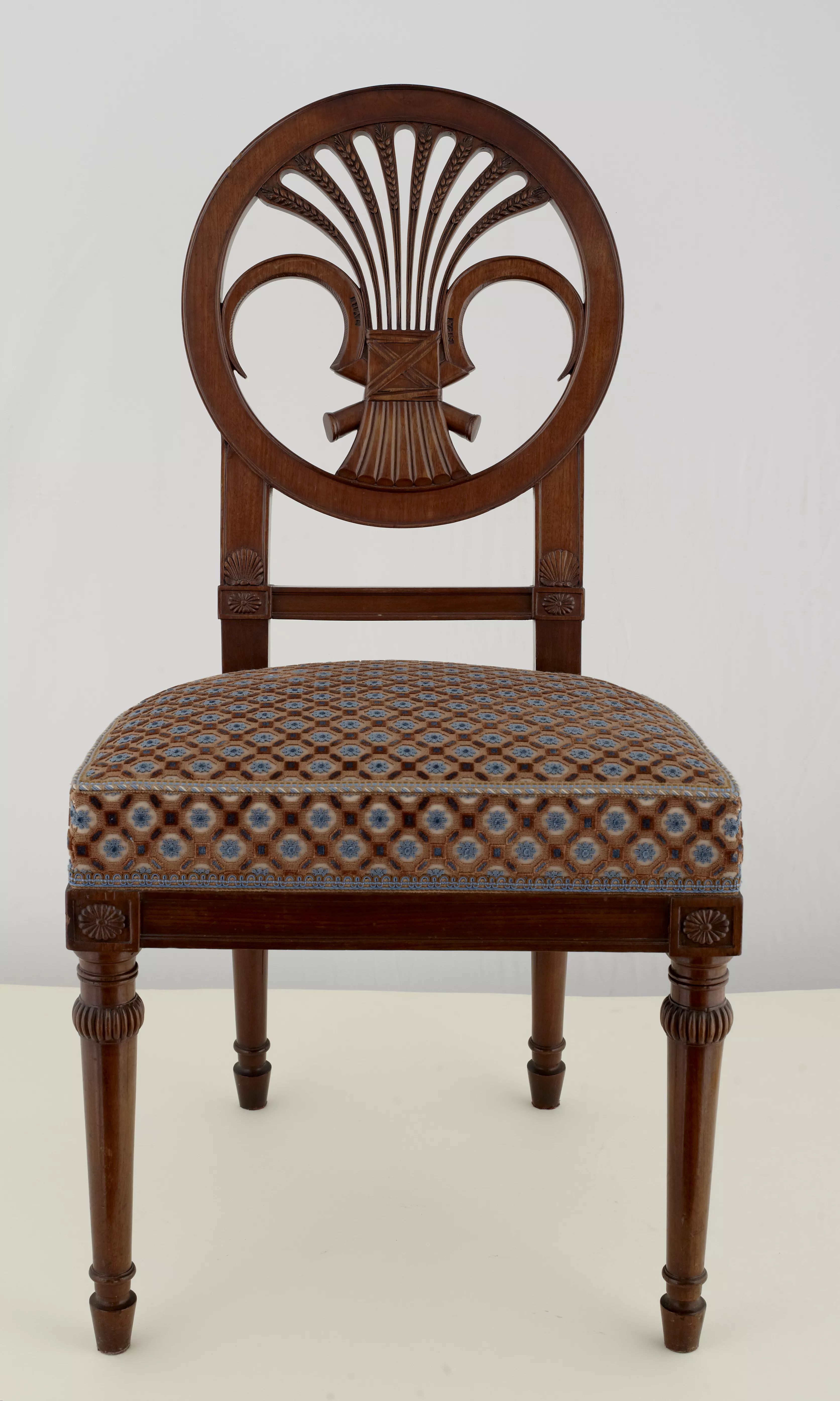 Photographie d'une chaise à dossier rond avec motif à gerbe de blé associé à deux faucilles croisées