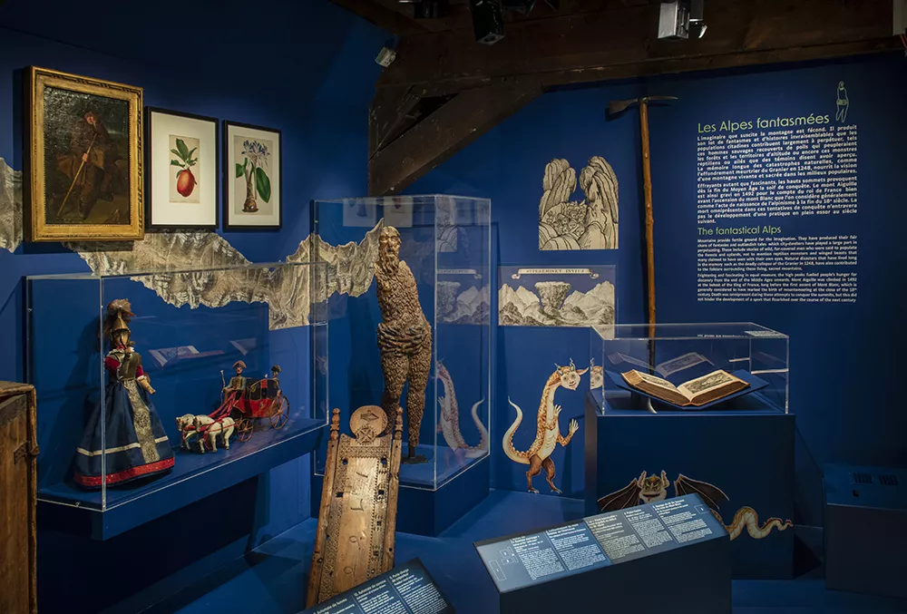 Photographie d'une salle de l'exposition &quot;Alpins&quot; présentant divers objets et tableaux témoignant des récits inspirés par le territoire alpin