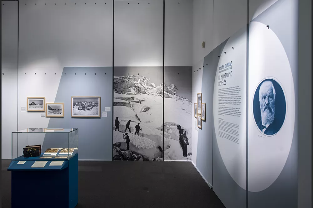 Photographie d'une salle de l'exposition &quot;Tairraz&quot; présentant des photographies de montagne en noir et blanc et une vitrine avec des négatifs