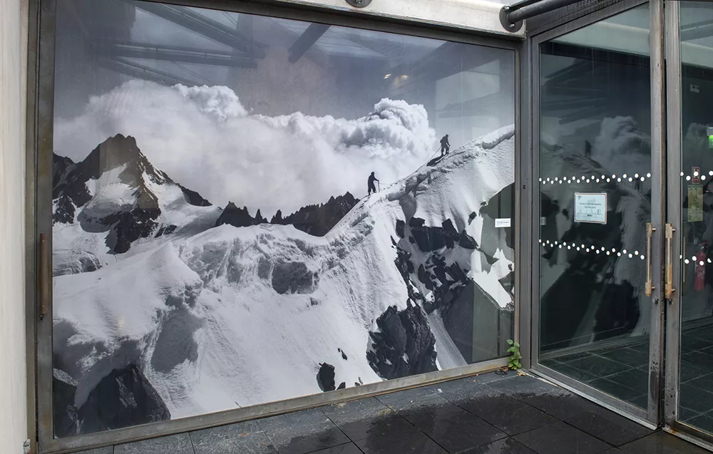 Photographie d'un couloir de l'exposition &quot;Tairraz&quot; montrant un agrandissement de photographie de montagne en noir et blanc sur un mur