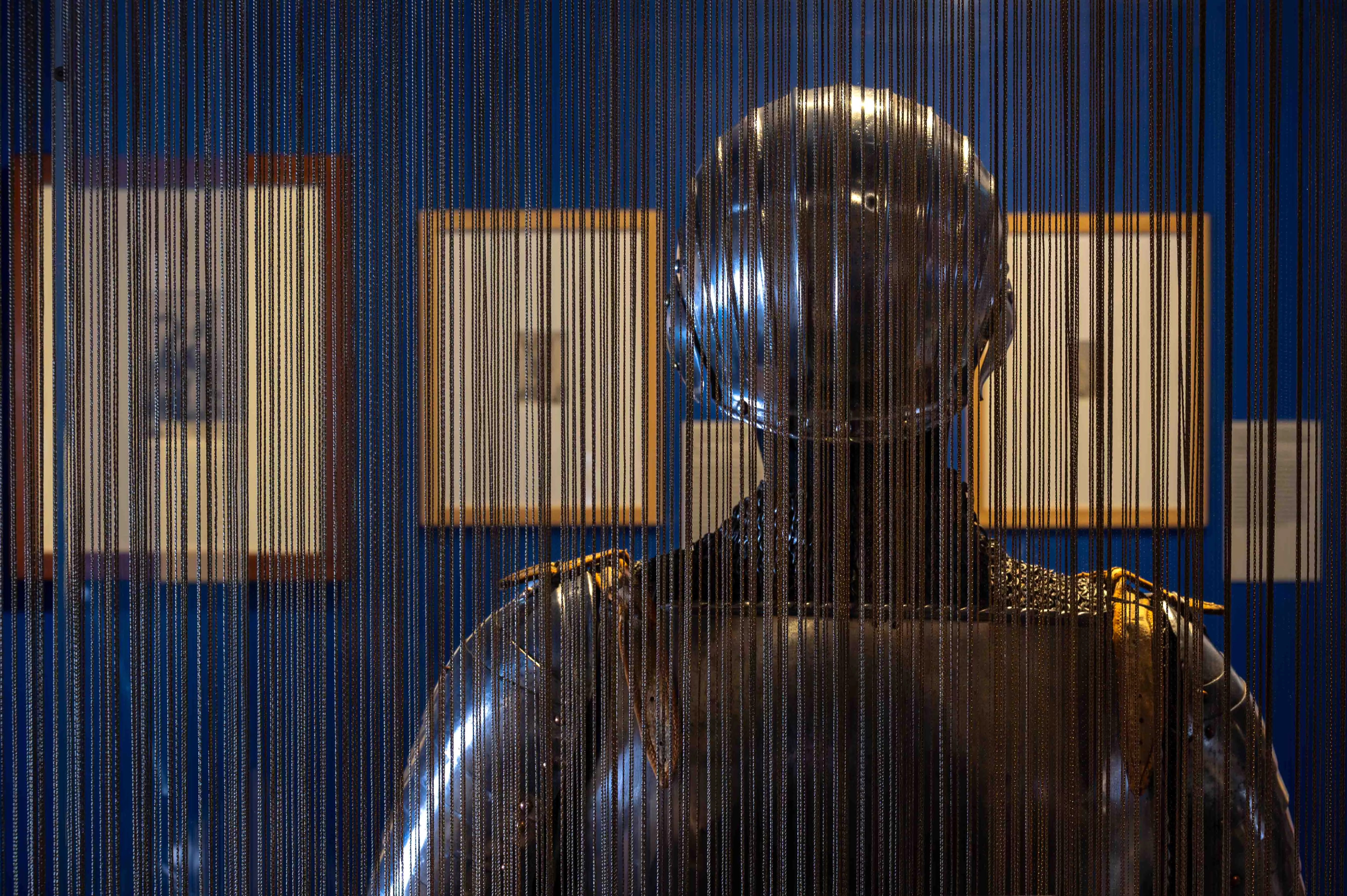 Exposition Sur un fil, ou l'art de se vêtir au Moyen Âge.  Demi-Armure de dos au travers le rideau