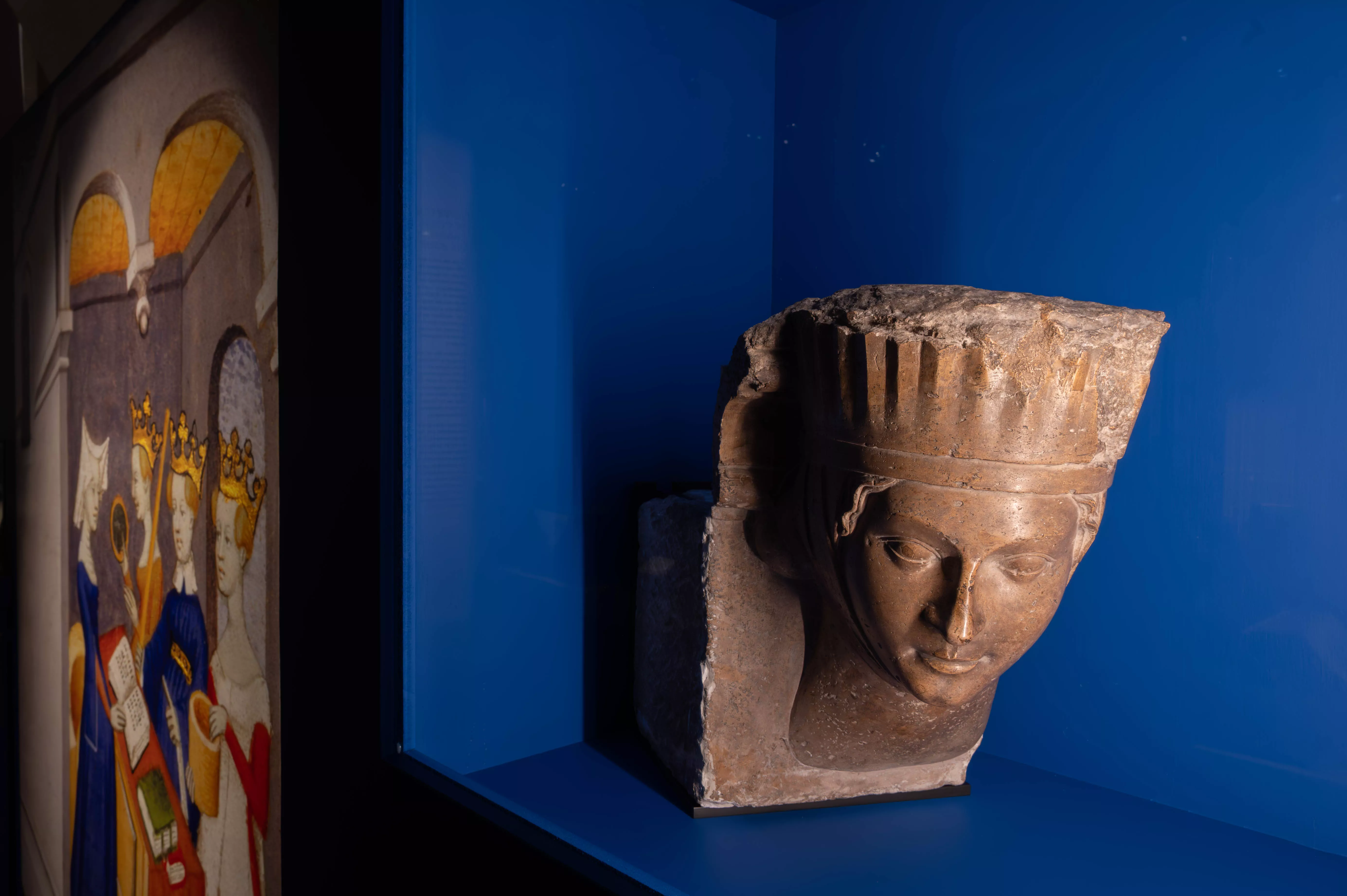 Exposition Sur un fil, ou l'art de se vêtir au Moyen Âge.© Fabian da Costa Exposition Sur un fil, ou l'art de se vêtir au Moyen Âge. Vue d'une vitrine  tête de femme sculptée en saillie sur une moulure