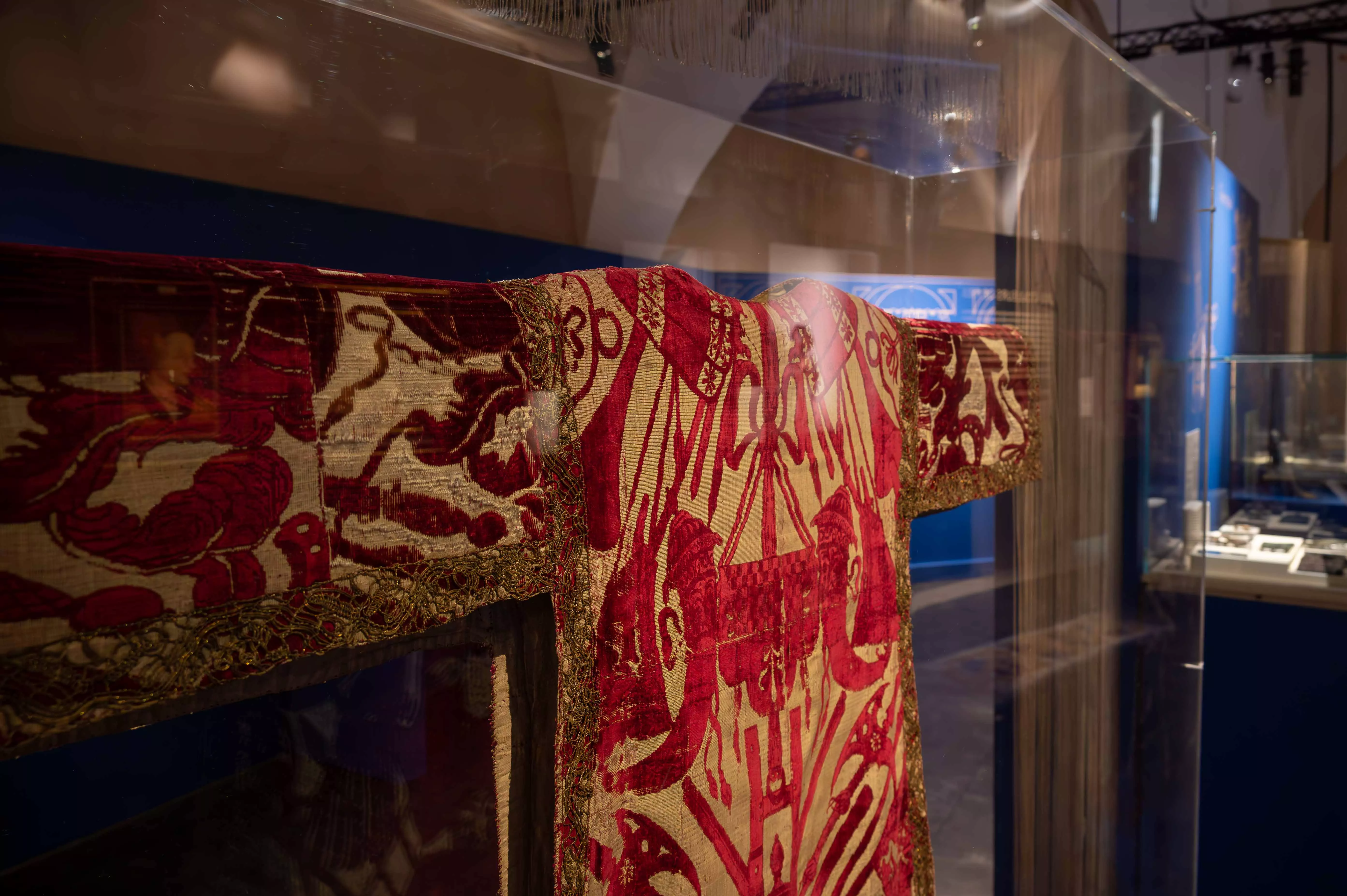 Exposition Sur un fil, ou l'art de se vêtir au Moyen Âge. Exposition Sur un fil, ou l'art de se vêtir au Moyen Âge. Vitrine dans laquelle se trouve un tabard venue d'Italie en velours ciselé, satin, dentelle, soie, argent et fil d'or