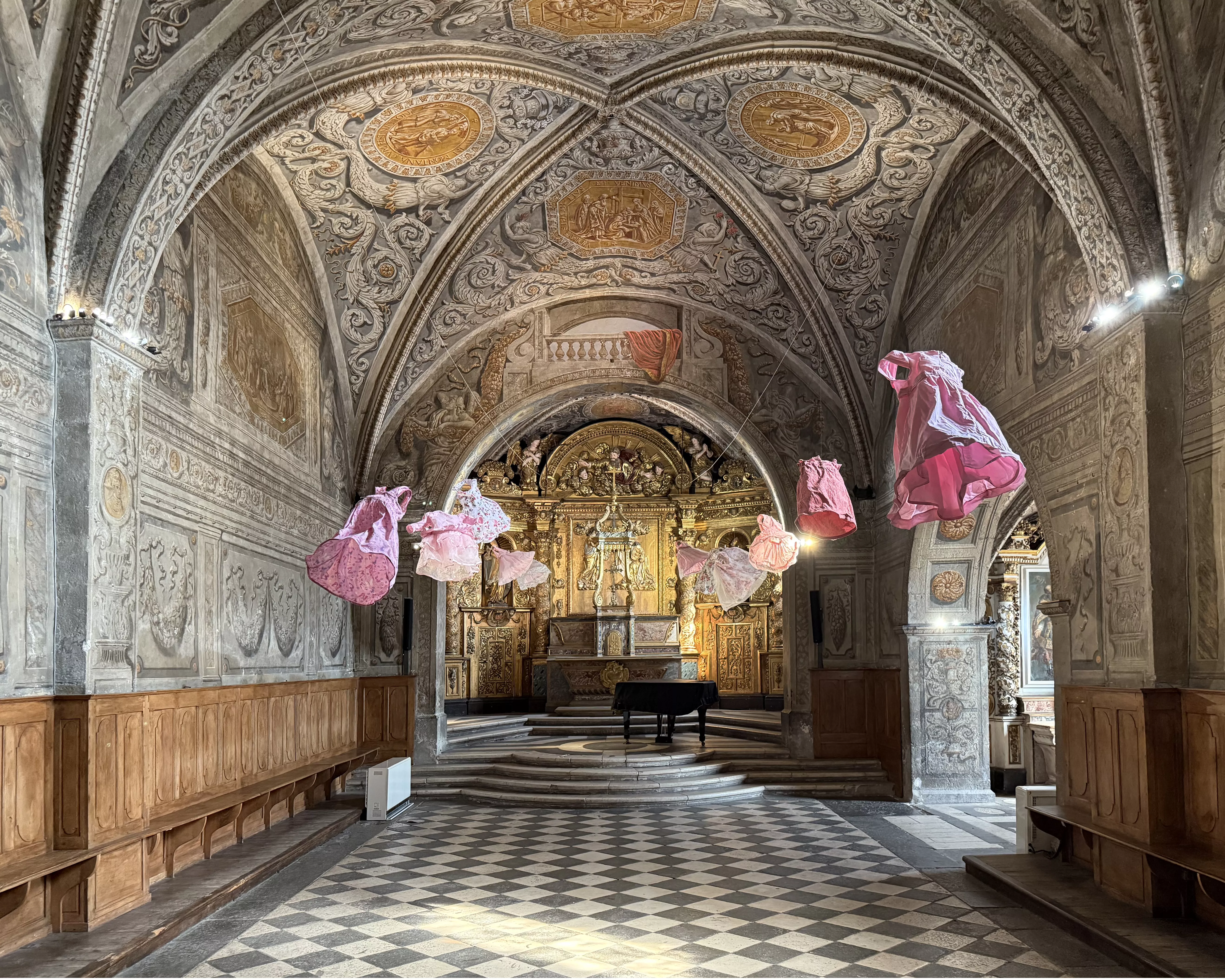 Installation de l'artiste Kaarina Kaikkonen : robes de petites filles roses flottant dans la chapelle baroque du musée dauphinois