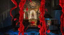 Photographie de l'intérieur de l'église Saint-Laurent avec au premier plan une installation en satin rouge rappelant des branches d'arbre fruitier © Yannick Siegel