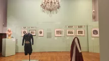Photographie d'une salle de l'exposition "Comment m'habillerai-je" au musée de la Révolution française montrant des tableaux et deux tenues d'époque (homme et femme)