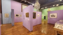 Photographie d'une salle de l'exposition "Comment m'habillerai-je" au musée de la Révolution française montrant des tableaux, des cocardes et une tenue d'époque dans une scénographie verte et violette