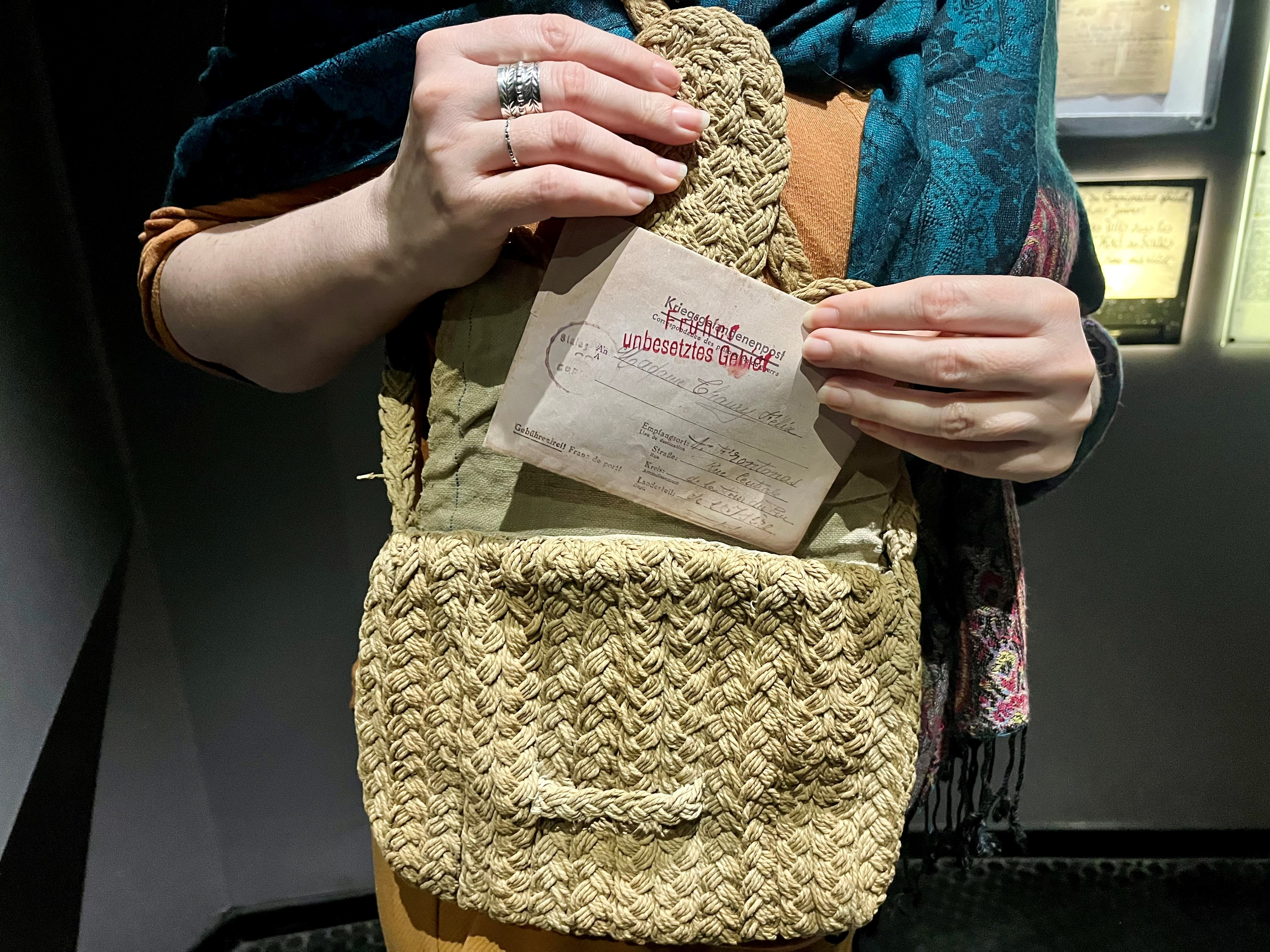 Photographie montrant des mains de femme sortant d'un sac à main une lettre de prisonnier de guerre rédigée en allemand