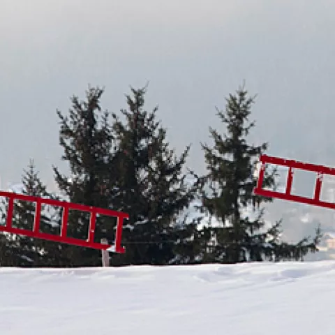 un homme et une femme habillés en rouge ou en bleu portant une échelle rouge dans un paysage de neige © Stéphanie Nelson
