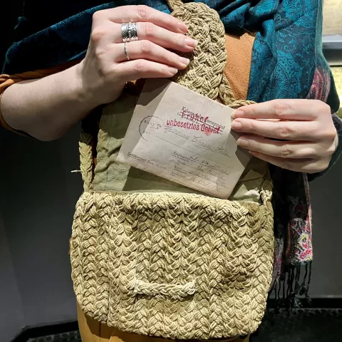Photographie montrant des mains de femme sortant d'un sac à main une lettre de prisonnier de guerre rédigée en allemand