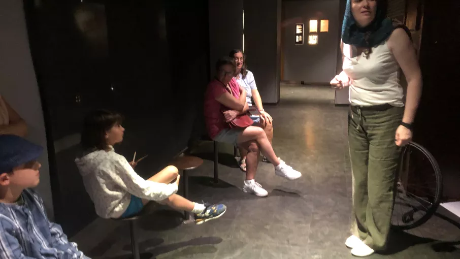 Photographie d'une visite contée au musée de la Résistance montrant une comédienne devant un public intergénérationnel