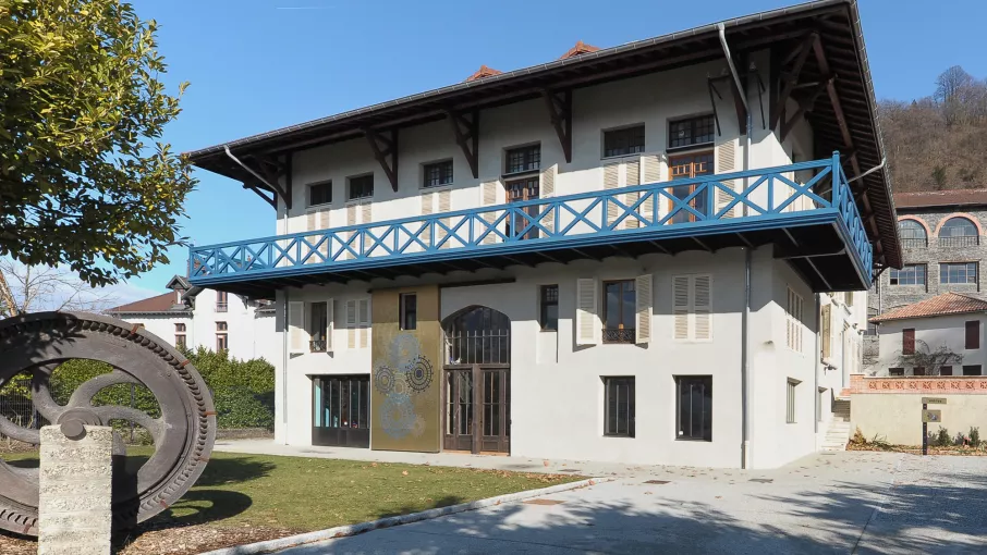 Maison Bergès à Lancey, au premier plan une des turbines autrefois installée dans la papeterie Bergès et à l'arrière-plan l'ancien laboratoire de l'usine