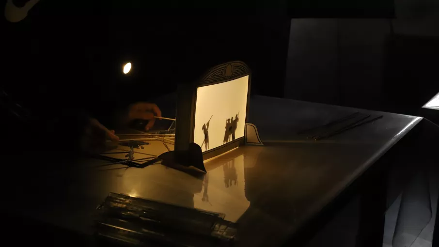 Un enfant joue avec des figurines dans un théâtre d'ombre. © Domaine de Vizille / Département de l'Isère