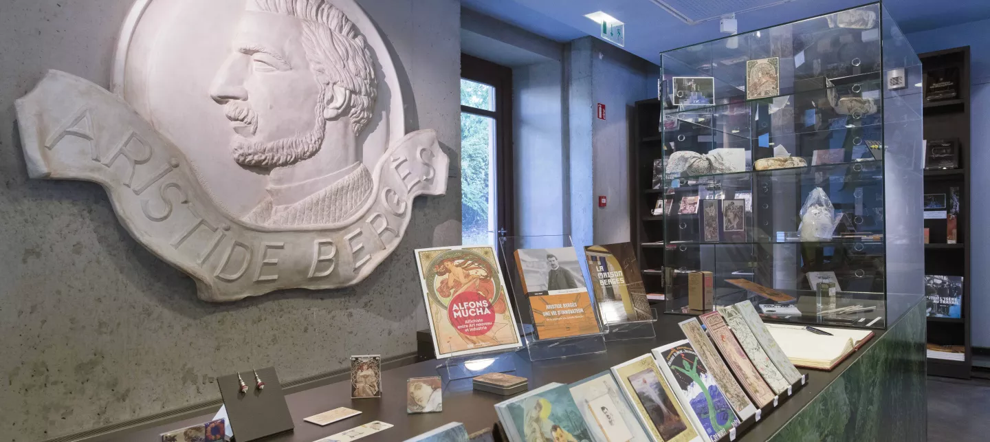 Accueil et boutique de la Maison Bergès : cartes postales au premier plan, magnets décoratifs, boucles d'oreilles, livres, règles...